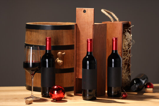 Bottles of wine, glass, wooden gift boxes, barrel corks and red Christmas balls on table