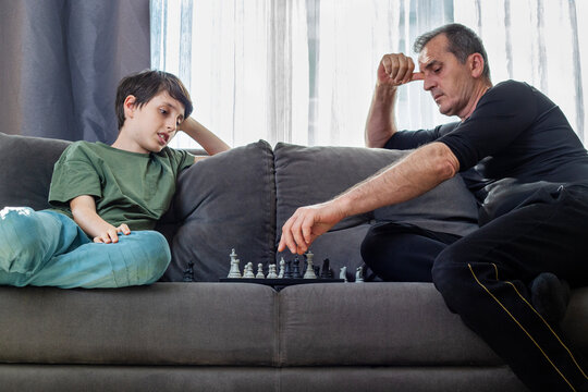 Father and son playing chess at home