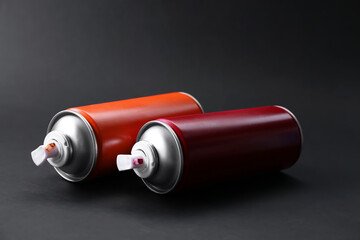 Two spray paint cans on dark gray background