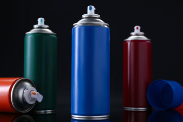Many spray paint cans on black background, closeup