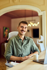 Portrait of a smiling man with mustaches, working over the laptop at the office.