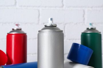 Cans of spray paint near white brick wall