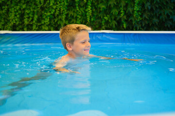Young boy is happily swimming in a backyard pool during a summer day