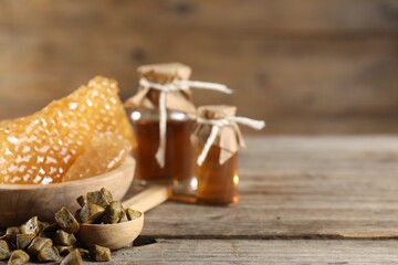 Natural honey tincture, propolis granules and sweet honeycombs on wooden table, closeup. Space for text