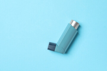 Asthma inhaler on light blue background, top view. Space for text