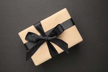 Gift box with satin bow on black background, top view