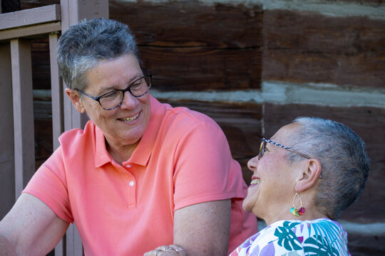 Older gay couple smiling and chatting on porch