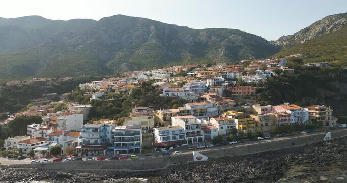 Seaside Townhouses In Cala Gonone Surrounded By Mountains In Sardinia, Italy. aerial shot