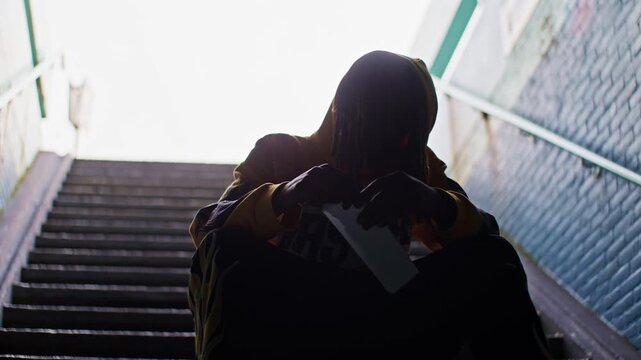 a man guy male boy black african model rips and burns paper with lighter while sitting on the steps of ladder