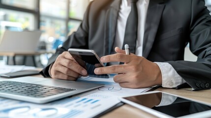 Businessman using smartphone, laptop, and tablet at work