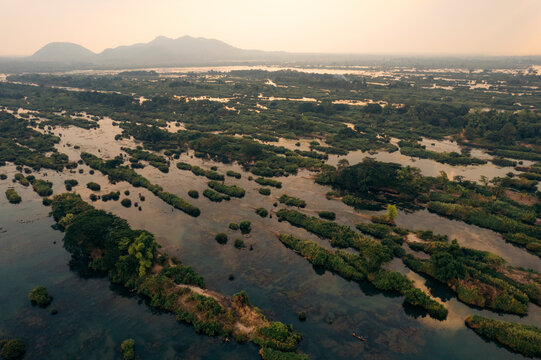 Small islands with green vegetation in clear water at twilight in the Four thousand islands area (Si Phan Don) in southern Laos; Champasak Province, Laos