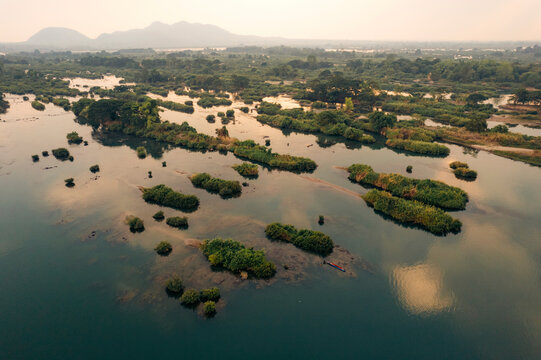 Small islands with green vegetation in clear water at twilight in the Four thousand islands area (Si Phan Don) in southern Laos; Champasak Province, Laos