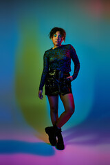 Obraz premium A vibrant African American woman striking a pose in a short skirt paired with stylish boots.