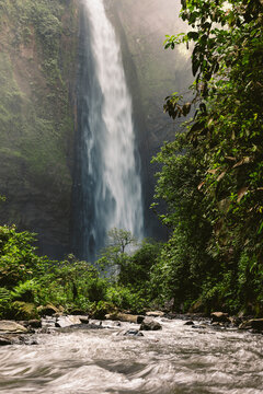 Motion blur and dramatic splashes from a high waterfall and lush vegetation at Air Terjun Kabut Pelangi, Indonesia; Kecamatan Pronojiwo, Kabupaten Lumajang, Jawa Timur, Indonesia