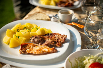 simple and tasty menu, natural potatoes soaked in butter and flavored with parsley and barbecued pork, at a garden party in a summer afternoon