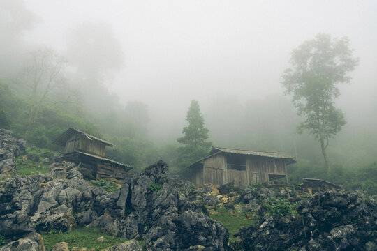 Traditional wooden structures built on a rocky terrain in the fog in a village in Son La, Vietnam; Ta So village, Moc Chau District, Son La, Vietnam