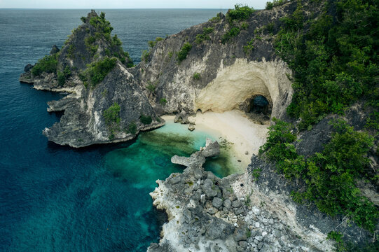 White sand beach with natural arch along a rugged coastline in the Molucca Sea, in Central Sulawesi, Indonesia; Tanjung Gundul Pasir Putih, Banggai Islands Regency, Central Sulawesi, Indonesia
