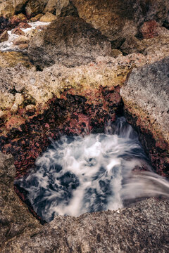 Water flows and splashes in a rocky gorge along the coast of Central Sulawesi, Indonesia; Tanjung Gundul Pasir Putih, Banggai Islands Regency, Central Sulawesi, Indonesia