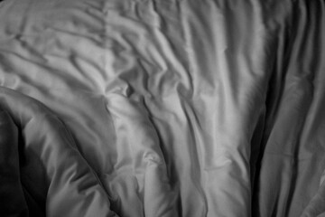 Wrinkled white fabric texture with soft folds and shadows, minimal abstract background suitable for design, textile, and concept use.