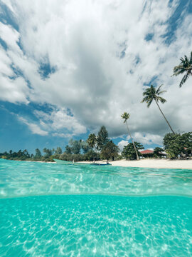 Split view of clear turquoise water and white sand of Pantai Oyama in Sulawesi Tengah, Indonesia