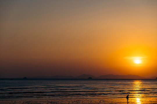 Man looking for valuable metals at sunset at Ao Nang Beach; Krabi, Thailand