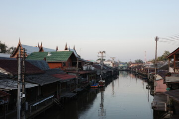 Traditional Thai riverside houses along a calm canal in Thailand during sunset, reflecting local culture, architecture, and peaceful waterfront lifestyle.