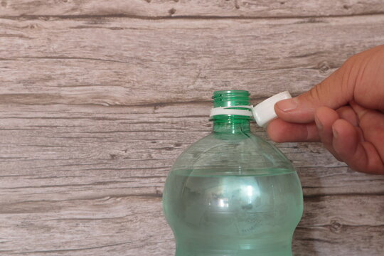 mano quitando tapo adosado botella 