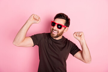 Naklejka premium Photo of overjoyed man with bristle dressed brown t-shirt in sunglass raising fists celebrate party isolated on pink color background