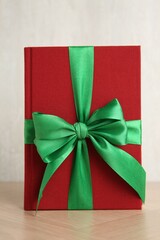 Hardcover book with ribbon as gift on wooden table