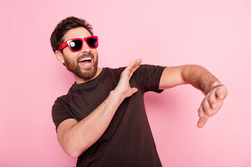 Photo of eccentric man with stylish bristle dressed brown t-shirt in sunglass dancing in night club isolated on pink color background