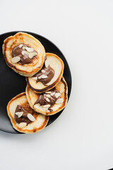 Plate of pancakes dripping with Nutella and almond crumbs with dark gray background.. Copy space for text. Mockup for menu, Pancake day