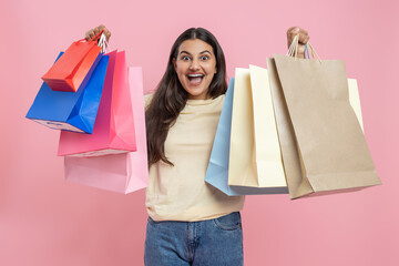Amazed woman wearing casual T-shirt and jeans showing shopping bags