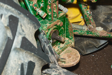 Detailed view of a tractor tire with deep grooves and rugged texture mounted on a yellow wheel. Ideal for themes related to agriculture, machinery, and industrial equipment.