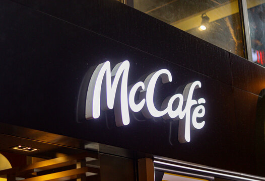 McCafe logo banner outdoors glowing in dark. Fast-food chain sign
