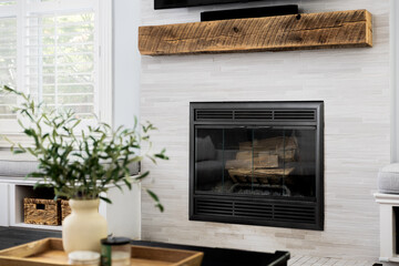 A fireplace detail with brown tiles in a cozy living room and a television mounted above.