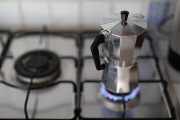A silver coffee pot is brewing on a stovetop burner