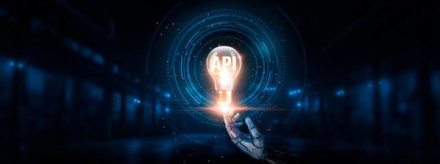 API Technology: Interoperability, efficiency, hand of robotic holding glowing API in light bulb on...