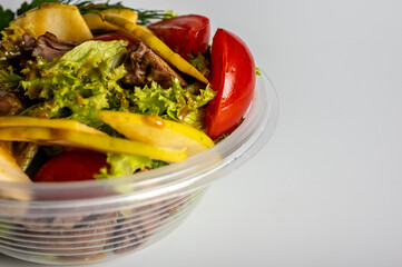summer salad, tomato salad, vegetables, in a plastic container on a light background, food delivery, takeaway food