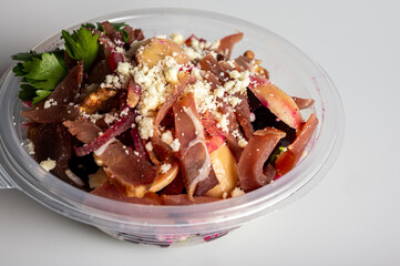 spring summer salad of beets and meat greens in a portable container on a light background, fast food delivery