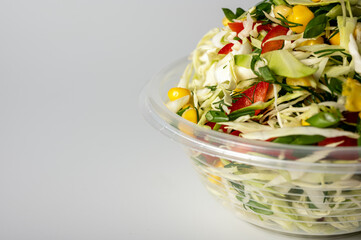 spring summer salad with green cabbage in a portable container on a light background, fast food delivery