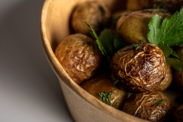 fried new potatoes cooked with golden skin, fast food delivery in kraft paper packaging on light background, place for inscription