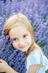 Portrait of cute little 5 year old girl with brown eyes in blue dress. Happy child in lavender field. Summer.