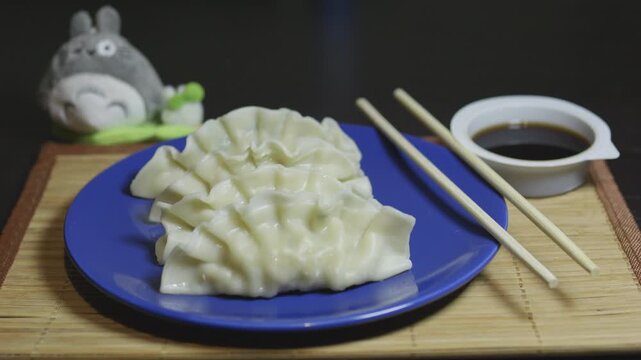 Dumplings gyoza mandu on a blue plate with wooden chopsticks.