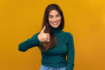 Positive beautiful woman doing ok gesturing with fingers while posing at the camera on isolated yellow