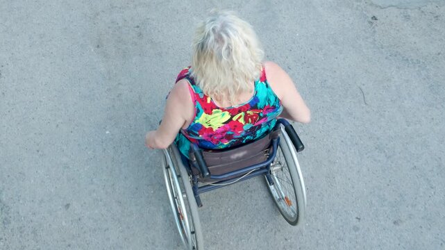 Disabled white woman in a wheelchair on the street. Outdoor walk of woman in wheelchair