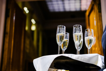 Waiter Holding Tray with Champagne Flutes. Waiter holding a tray with champagne flutes, ready to serve at a formal event. Horizontal photo