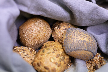 A close up of four different types of bread rolls nestled inside a linen bag
