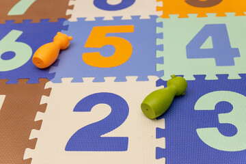 Mata do ćwiczeń dla malucha, na której leżą gumowe zabawki. Jedna z nich jest pomarańczowa i ma kształt misia, a druga jest zielona i przedstawia małpkę. Tło jest jasne, a cała scena sprawia wrażenie  © Clear Emotion