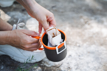 An individual is displaying attention to detail by delicately placing a packet of coffee into a cup on a table, highlighting their focus and precision in the task at hand