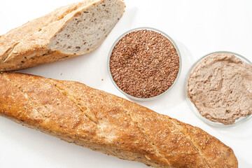Baguette with rye flour and flax seeds on a white table with petri bowls with ingredients